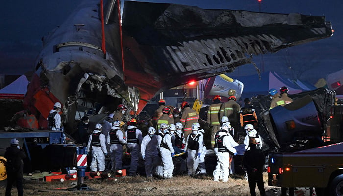 Firefighters and rescue personnel carry the body of a victim near the scene where a Jeju Air Boeing 737-800 series aircraft crashed and burst into flames at Muan International Airport in South Jeolla Province, on December 29, 2024. — AFP