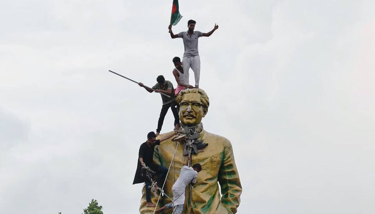 People climb the statue of Sheikh Mujibur Rahman at the Bijoy Sarani area, as they celebrate the resignation of the PM Sheikh Hasina in Dhaka, Bangladesh on August 5, 2024. — Reuters