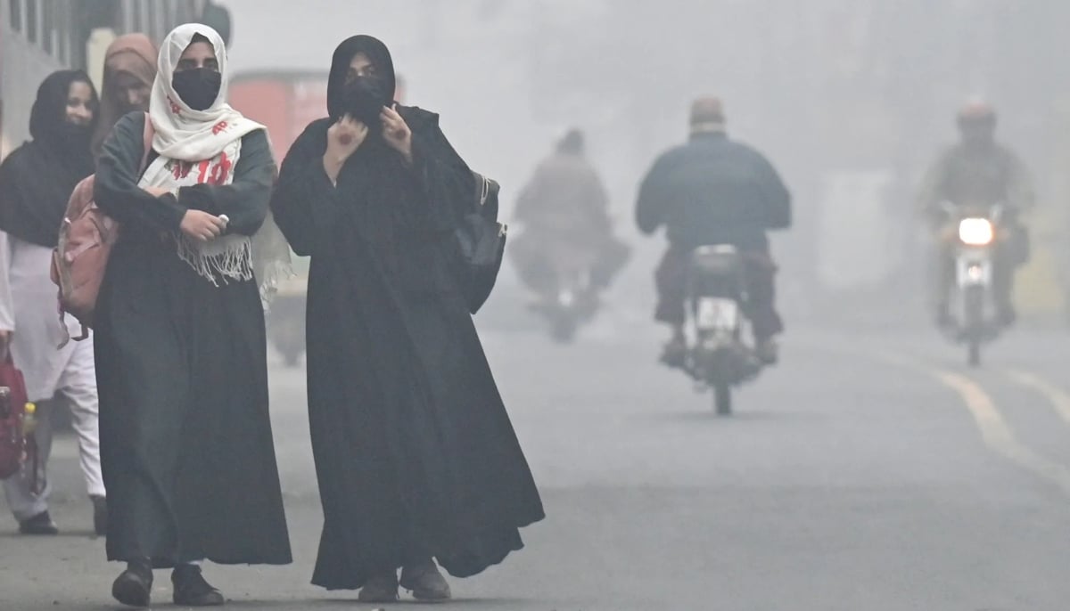 Women walk on a Lahore street amid heavy smog in on November 14, 2024. — AFP