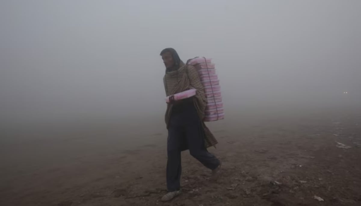 A vendor carries plastic boxes on a smoggy morning in Lahore, January 3, 2019. — Reuters