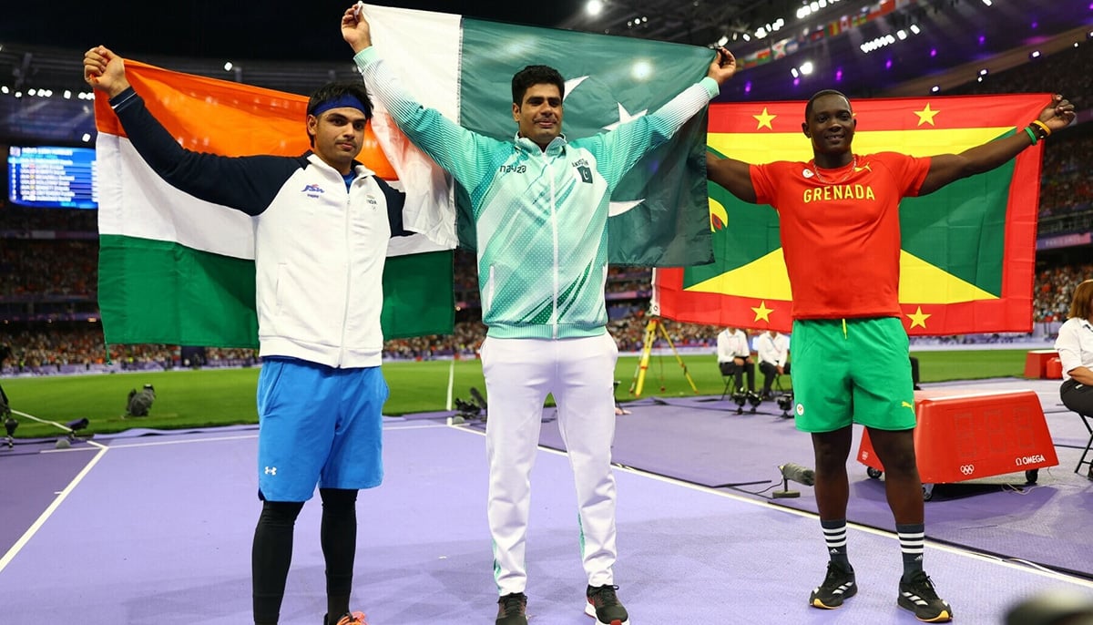 Arshad Nadeem (centre) celebrates with Pakistan’s flag after winning gold with silver medallist Neeraj Chopra of India (left) and bronze medallist Anderson Peters of Grenada at Mens Javelin Throw Final at Stade de France, Saint-Denis, France on Aug 8, 2024. — Reuters