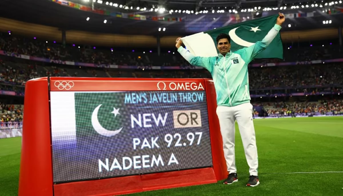 Arshad Nadeem of Pakistan celebrates with his national flag after winning gold as he stands next to a screen displaying his new Olympic record. — Reuters/File