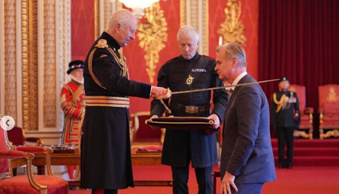 Christopher Nolan reacts as he receives knighthood from King Charles