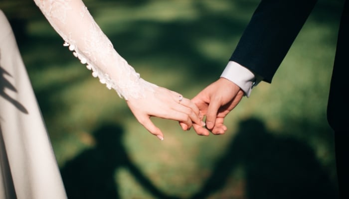 This representational photograph shows a couple holding hands. — Canva