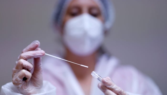 A medical worker holds a test tube at a testing centre in Les Sorinieres near Nantes, in France, on October 15, 2021. —Reuters