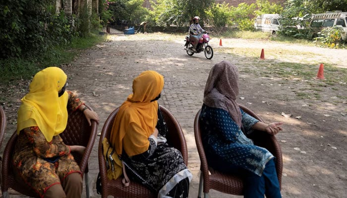 Ishrat Khan practices riding a motorbike as others watch her, during a training session as part of the Women on Wheels program organised by the traffic police department in Lahore on October 1, 2024. — Reuters