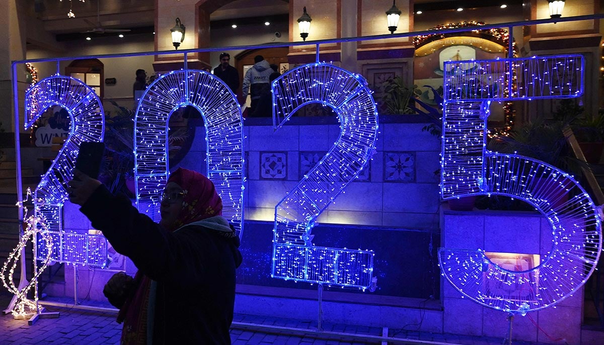 A woman takes her selfie in front of an illuminated decoration displayed on New Year´s Eve in Islamabad on December 31, 2024. — AFP