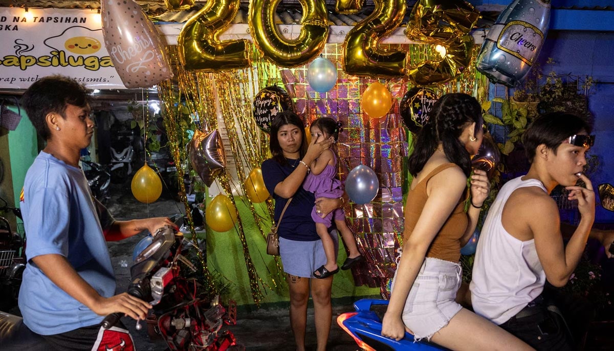 A woman covers a childs ear during New Year celebrations on a street in Mandaluyong City, Metro Manila, Philippines, December 31. — Reuters