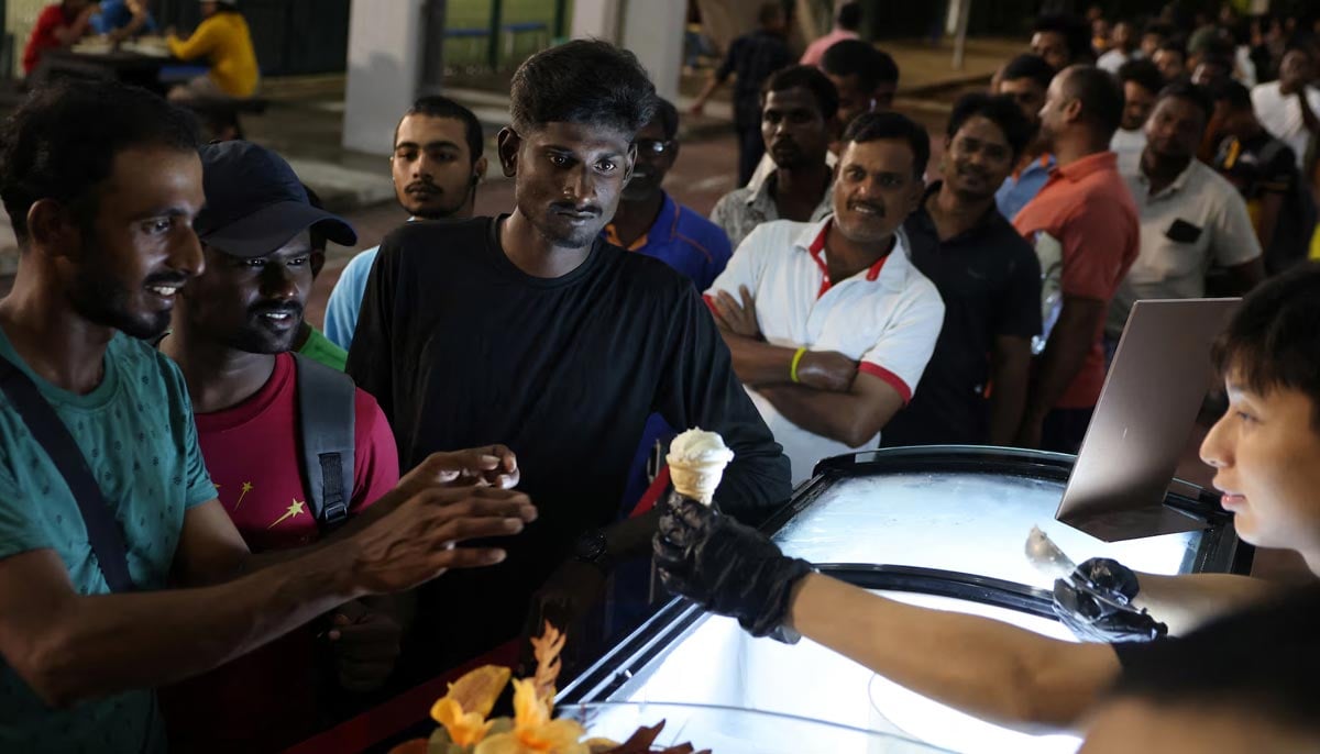 Bangladeshi and Indian migrant workers queue for free ice cream during New Year’s Eve celebrations at a migrant worker recreation center in Singapore, December 31. — Reuters