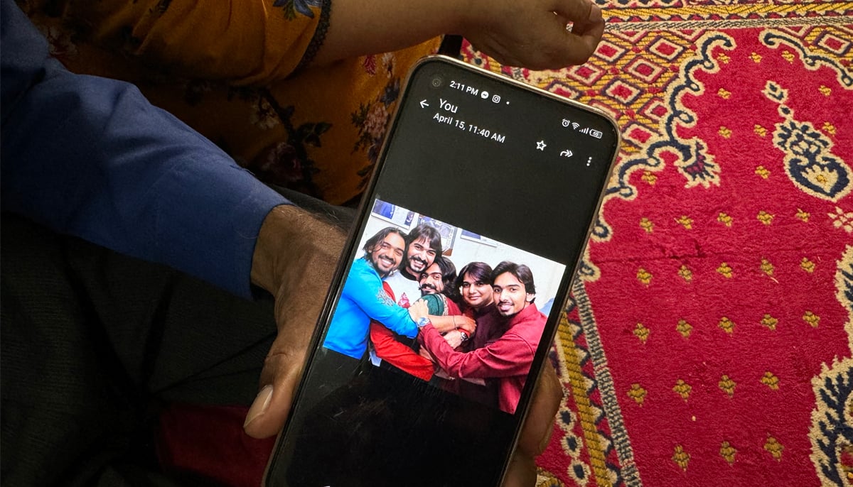 Syed Akhtar Hussain, father of Syed Ali Rehbar, shows a photo on his smartphone with Rehbar seen on the extreme left. — Photo by author