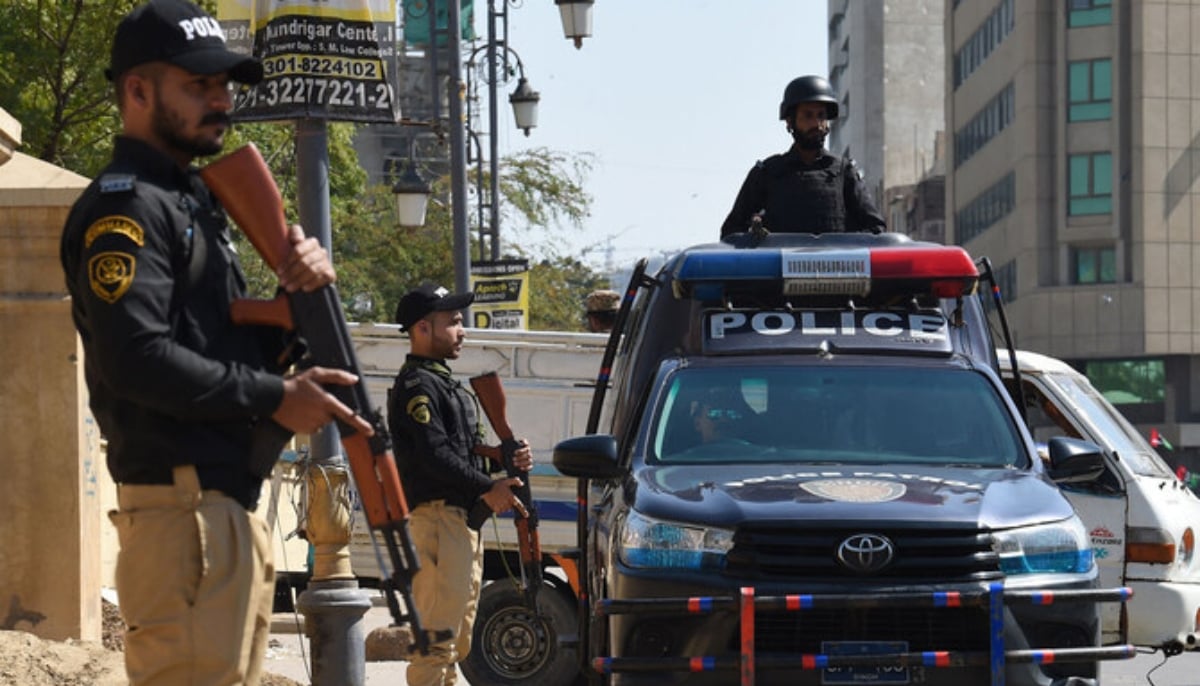 Policemen stand guard outside a polling station during the general elections in Karachi on February 8, 2024. — AFP