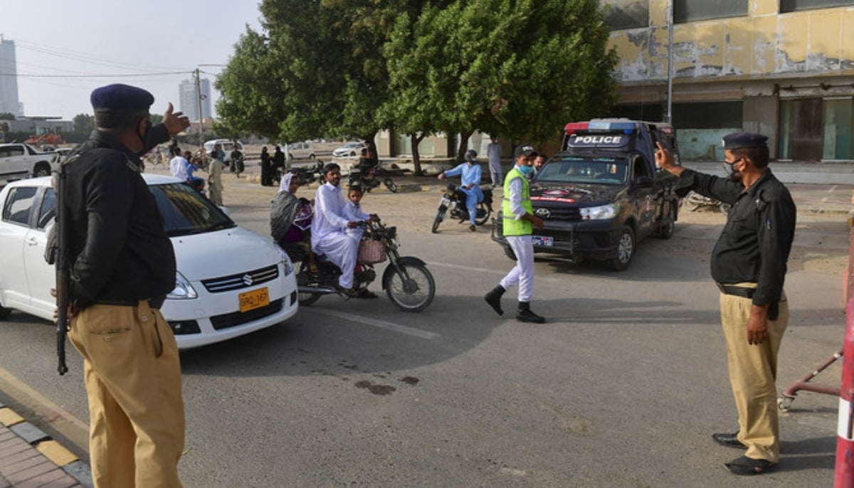 Policemen stop people at a checkpoint in Karachi on May 13, 2021. — AFP